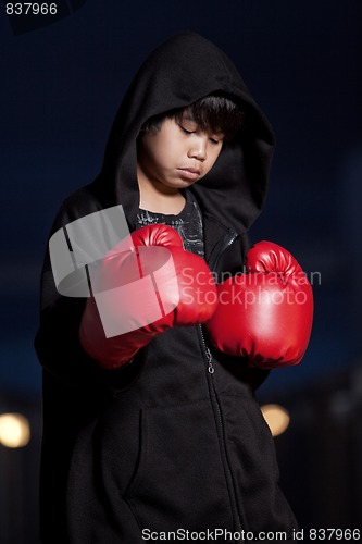 Image of Young intense asian boy wearing boxing gloves