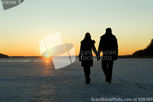 Image of Couple walking on ice at sunset