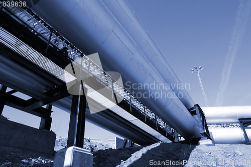 Image of industrial pipelines on pipe-bridge against blue sky