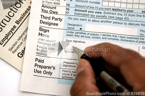 Image of Hand signing a tax form concept of filing tax