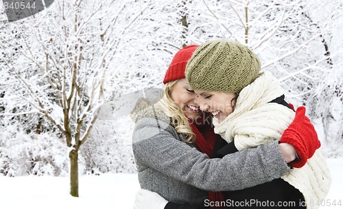 Image of Two girl friends hugging outside in winter