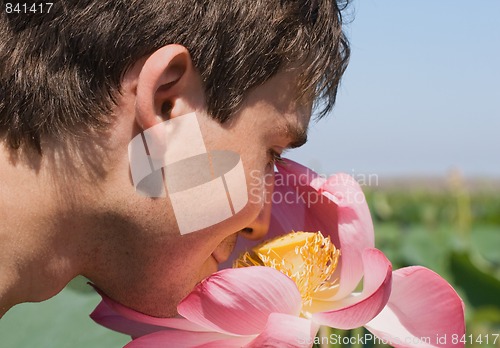 Image of Young man smelling a pink lotus