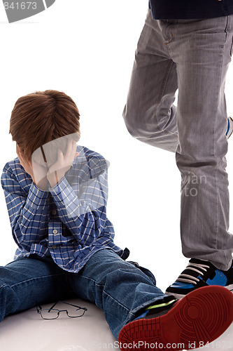 Image of child crying on the floor being kicked by a teenager