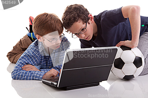 Image of two boys sitting on the floor playing computer, one holding a football