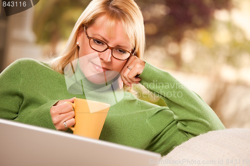 Image of Beautiful Woman Enjoys Her Warm Drink and Laptop