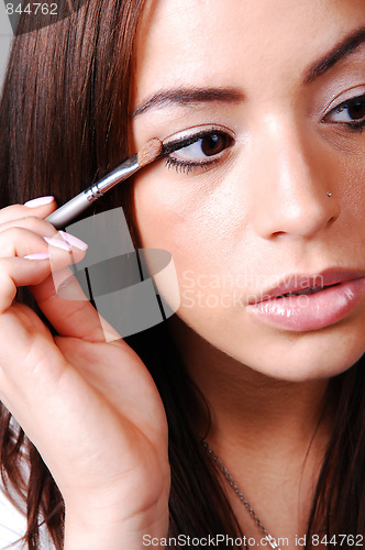 Image of Young woman putting makeup.
