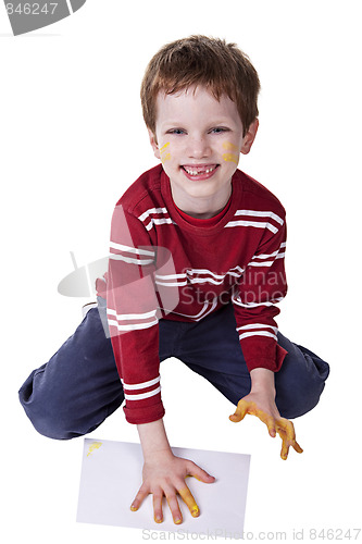 Image of Children playing with paint, stamping his hand on a white sheet