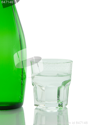 Image of Bottle and glass of mineral water reflected on white background