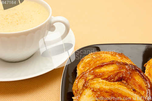 Image of Closeup of coffee with milk in white cup and a palmier pastry