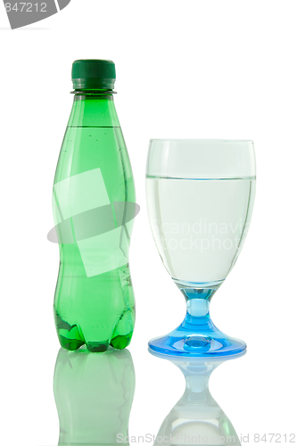 Image of Bottle and glass of mineral water reflected on white background