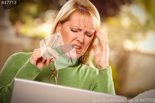 Image of Grimacing Woman Using laptop Suffering a Headache