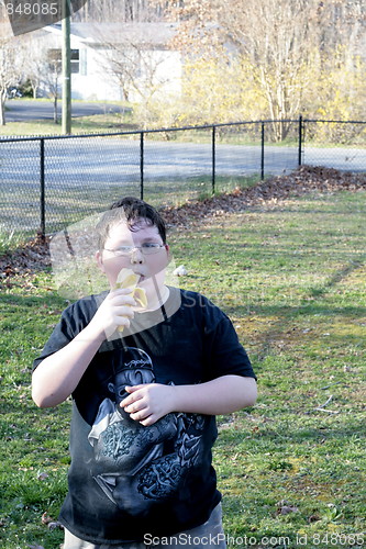 Image of Young boy eating banana outside