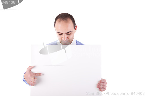 Image of Young businessman holding a white board and pointing, looking down