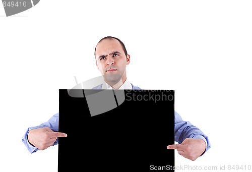 Image of young business man holding a blackboard and pointing with both hands, looking bored