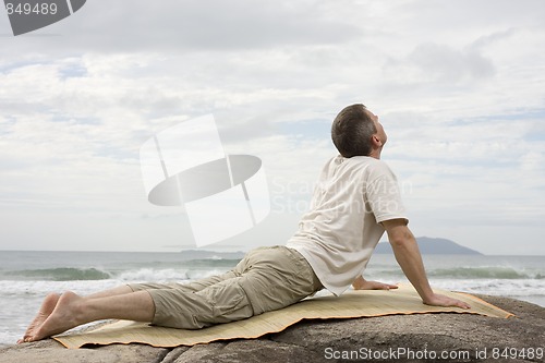 Image of Mature man doing yoga at the sea