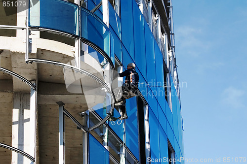 Image of Builder fixing glass on tall building