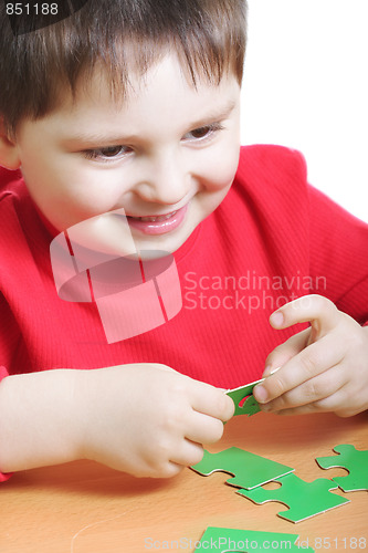 Image of Smiling kid assembling green puzzles