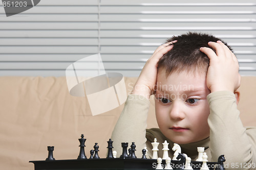 Image of Little chess player embracing head
