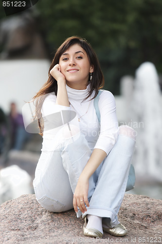 Image of Woman in casual sitting on stone