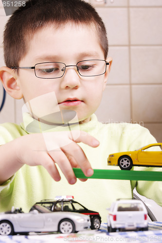 Image of Boy in green playing with cars