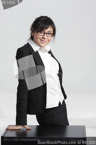 Image of Smiling businesswoman leaning on desk