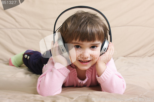 Image of Smiling girl with headphones on sofa