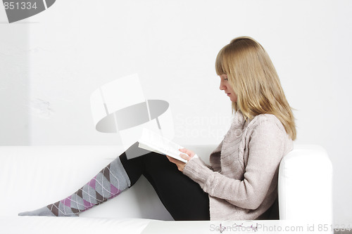 Image of Young blonde woman reading book sideview