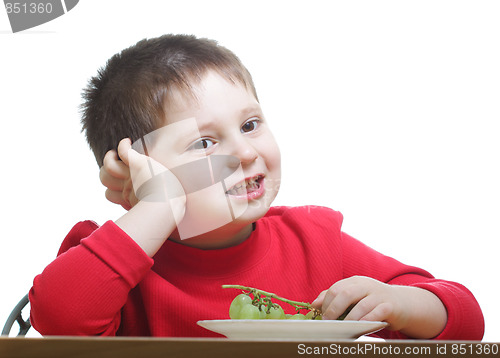Image of Cute boy in red eating grapes
