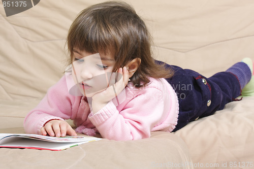 Image of Little girl reading on sofa