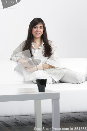 Image of Positive brunette sitting on sofa