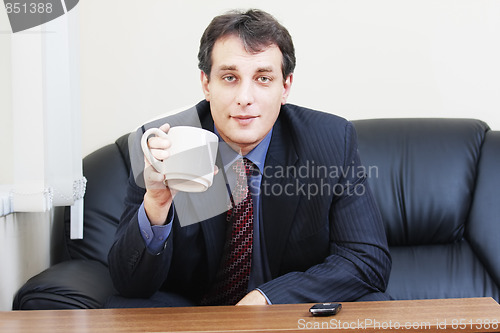 Image of Businessman with cup sitting on sofa