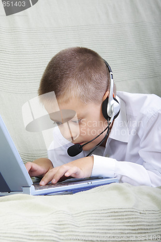 Image of Serious boy in headset working on laptop