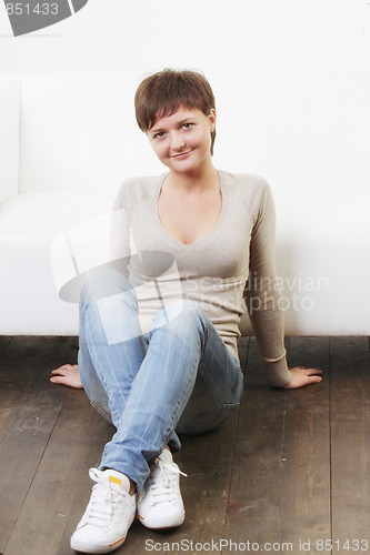Image of Smiling woman in casual sitting on floor