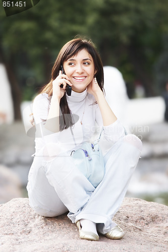 Image of Woman sitting on stone with cellphone
