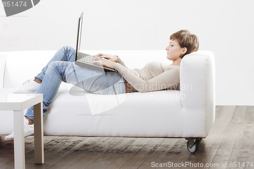 Image of Young woman on white sofa with computer