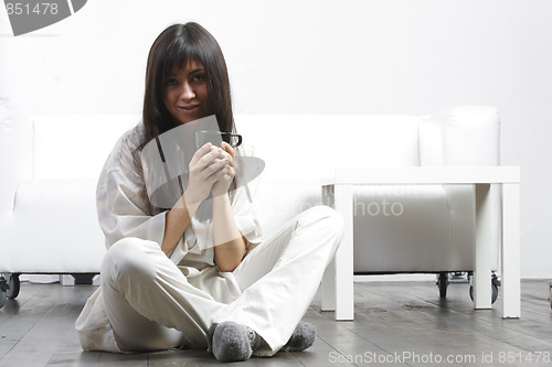 Image of Brunette with cup sitting on floor