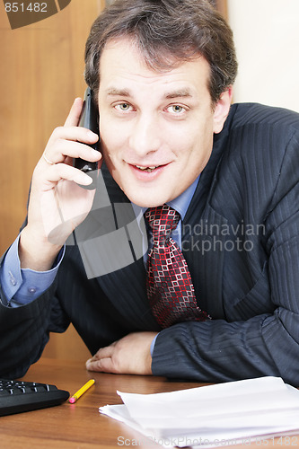 Image of Smiling businessman at desk with phone