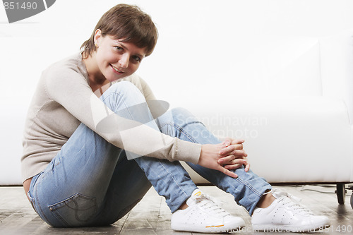 Image of Smiling woman sitting on floor sideview