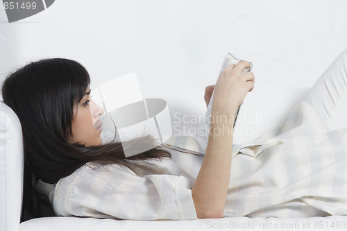 Image of Brunette with book laying down on sofa
