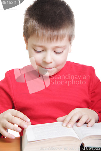 Image of Smiling kid in red reading book at desk