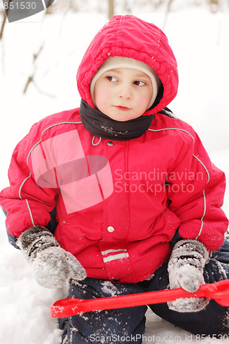 Image of Little kid in red jacket sitting with shovel