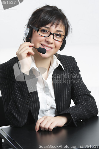 Image of Positive businesswoman with headset sitting at desk