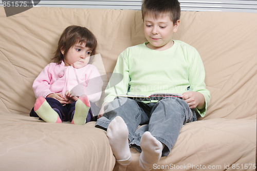 Image of Boy reading book to girl