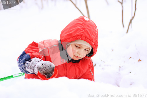 Image of Little kid in red jacket playing in snow