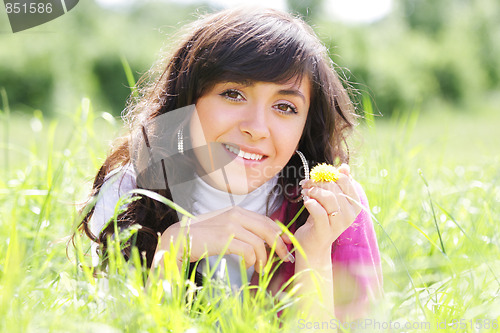 Image of Smiling brunette in grass with dandelion