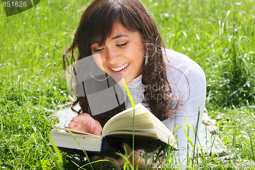 Image of Smiling brunette reading book on grass