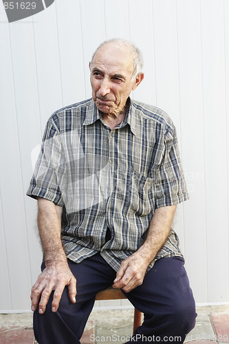 Image of Serious elderly man sitting on chair