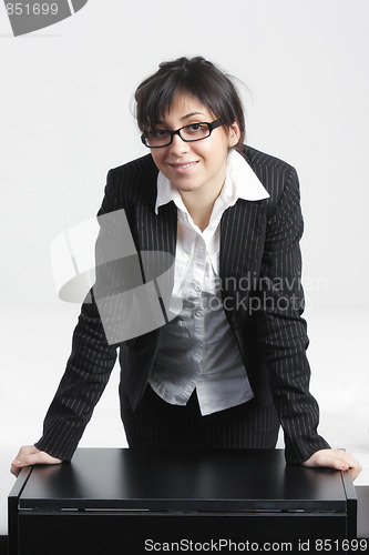 Image of Confident businesswoman leaning on desk