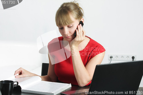Image of Businesswoman with cellphone reading magazine