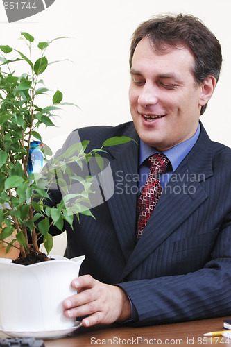 Image of Positive businessman watering plant